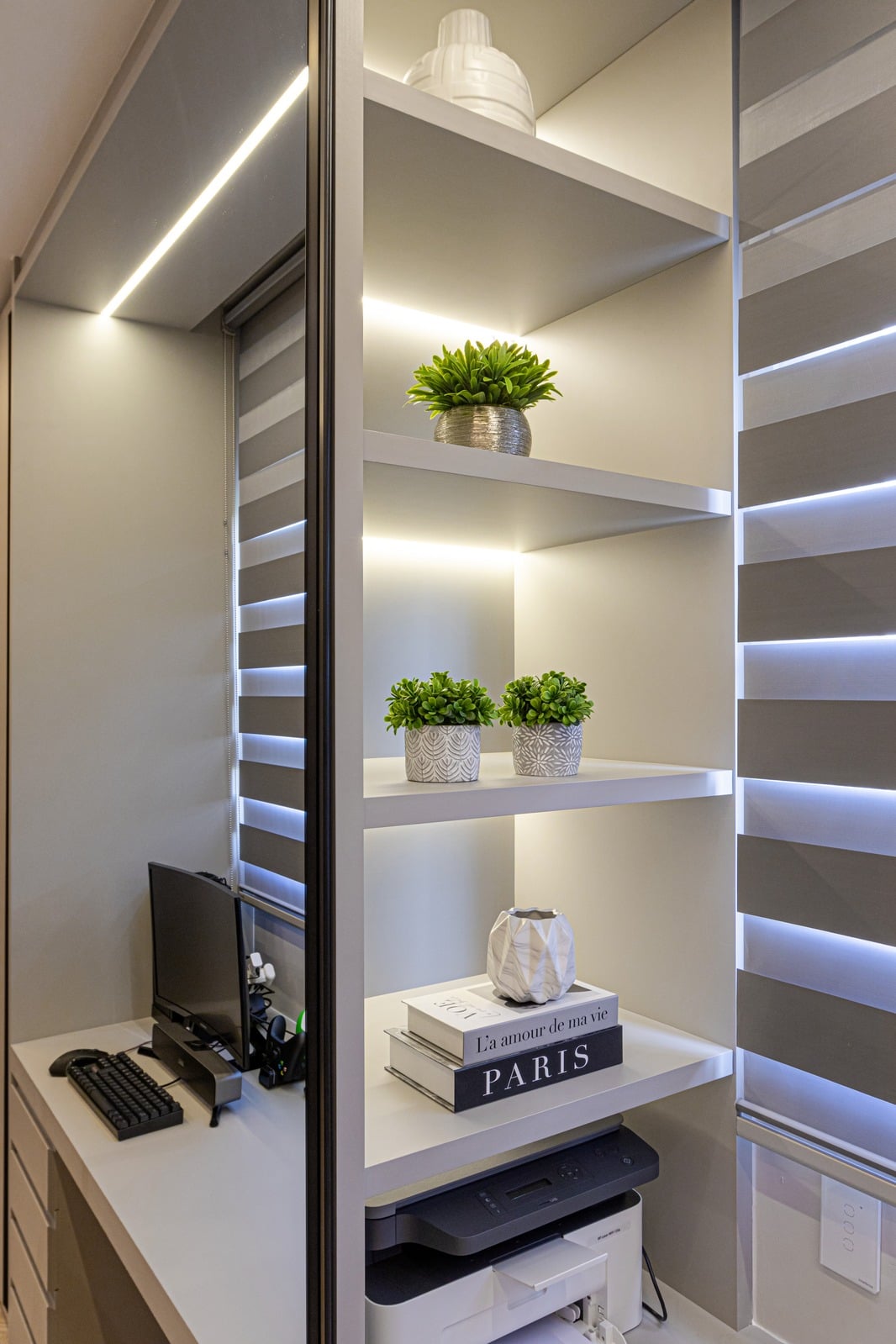 Escritório compacto com bancada, computador e nichos iluminados
